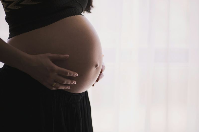 Femme enceinte tenant son ventre, ambiance lumière naturelle