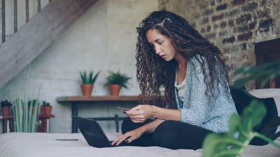 Achat en ligne sur ordinateur portable avec carte bancaire en main