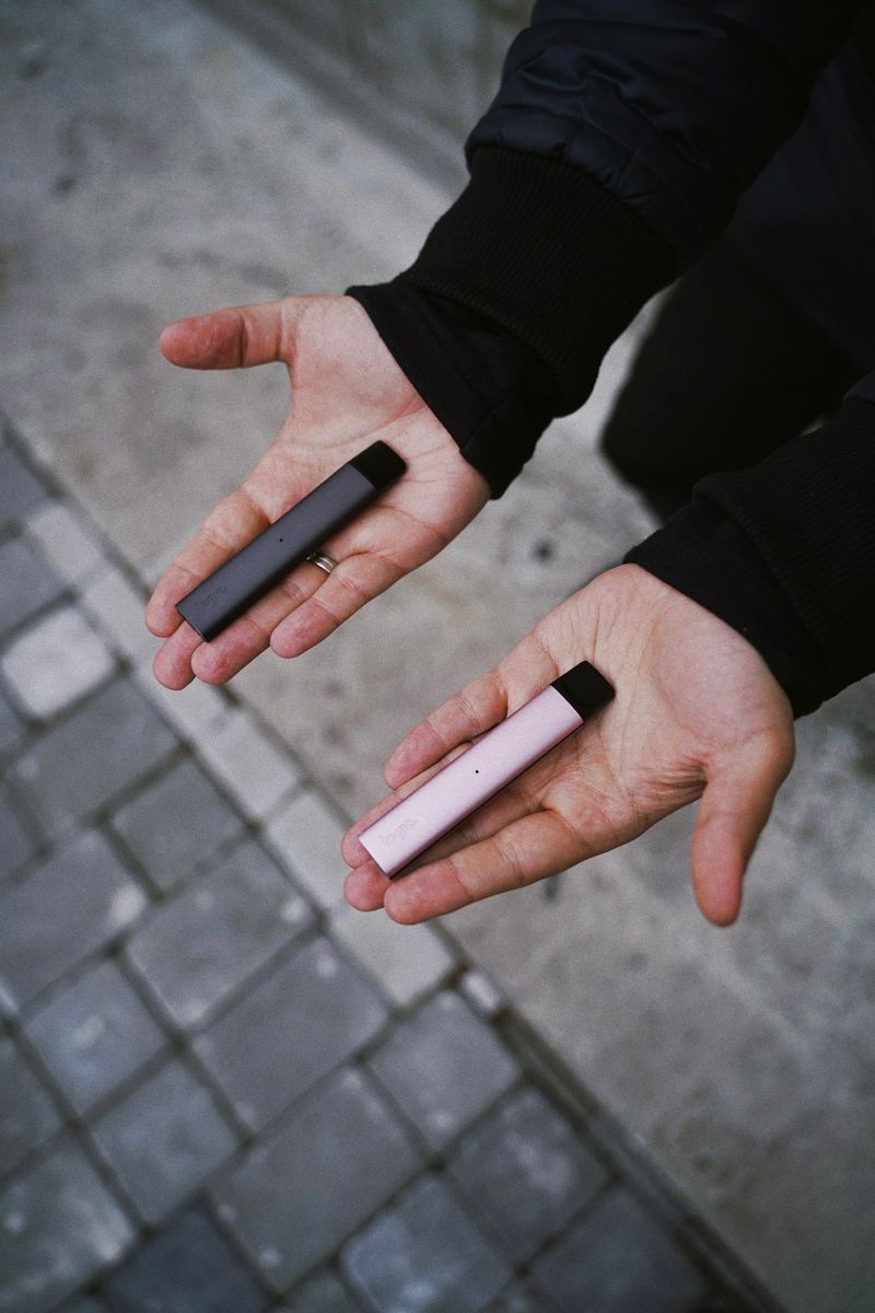 Deux pods modernes tenus en main, ambiance comparatif de cigarettes électroniques